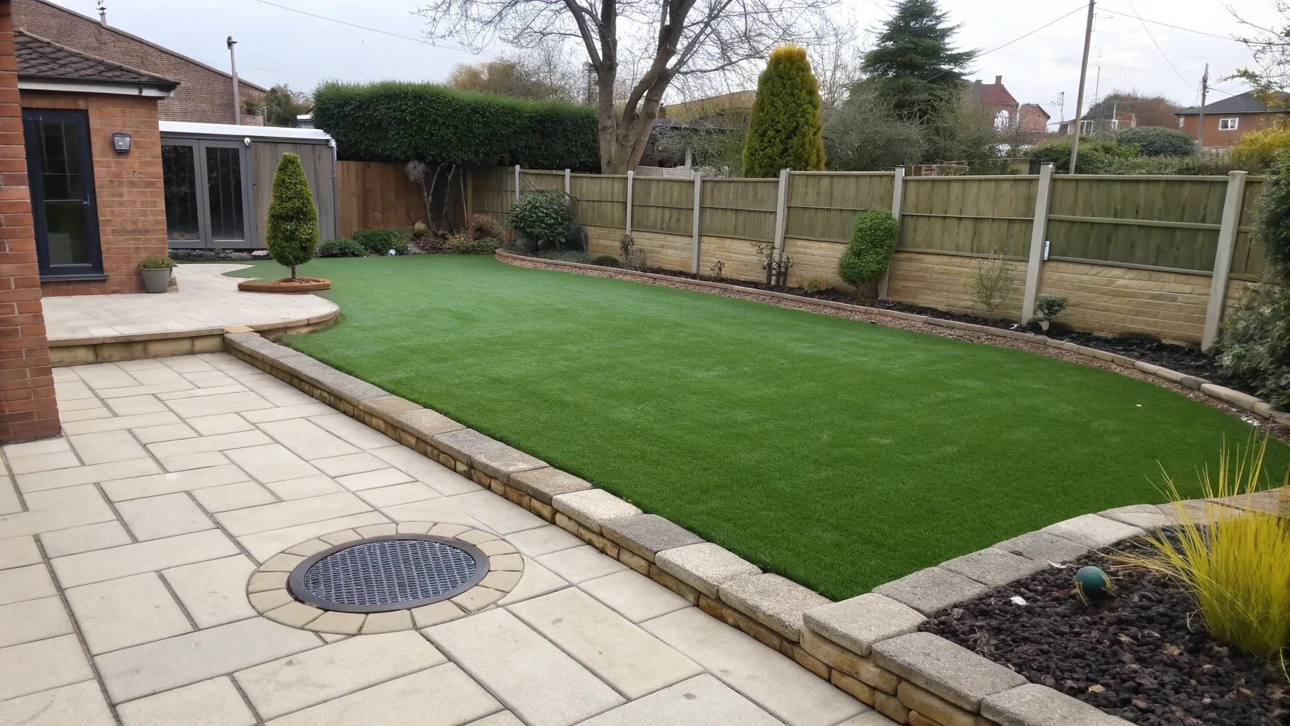 Freshly installed artificial grass surface with stone edging and drainage system in Birmingham garden no humans appears in the image