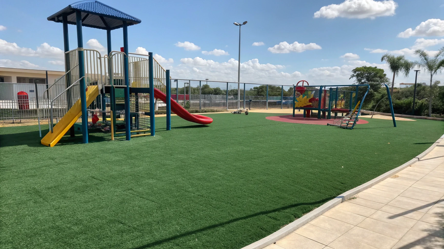 Safety-certified playground artificial grass surface with shock pad installation and colorful play equipment, no humans appear in the image